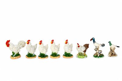 cinq figurines représentant des poulets et un chien, alignées les unes à côté des autres