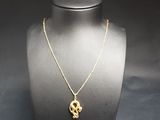 a gold necklace with a skull pendant on a mannequin