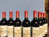 six bottles of red wine lined up on a wooden table