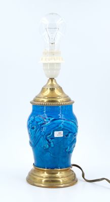 an image of a blue glass lamp with a gold base and a light bulb on top of it