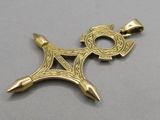 a close up of a gold pendant with a cross on it