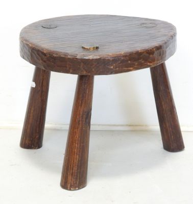 a small wooden stool with two legs on a white floor