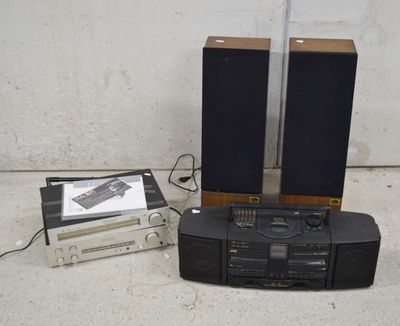 deux haut-parleurs, un lecteur de cassettes et un lecteur de CD posés par terre