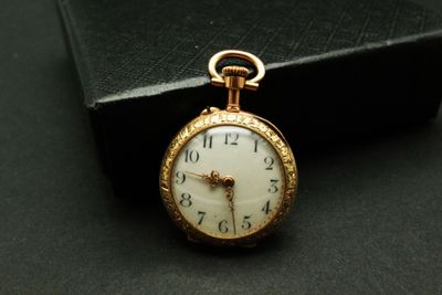 une montre de poche en or posée sur un coffret noir