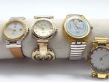four different watches are sitting on a napkin on a white surface