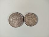 two silver coins sitting side by side on a white surface