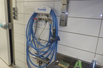 un tuyau bleu fixé au mur dans des toilettes publiques