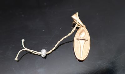 une médaille d'or ornée d'une croix, posée sur une table