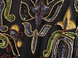 a close up of a black dress with a gold and green design