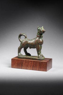 une figurine en bronze représentant un chien, posée sur un socle en bois