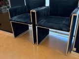 three black velvet chairs with chrome legs in a room