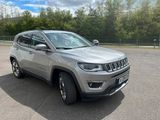La Jeep Compass est garée sur un parking, avec des arbres en arrière-plan.
