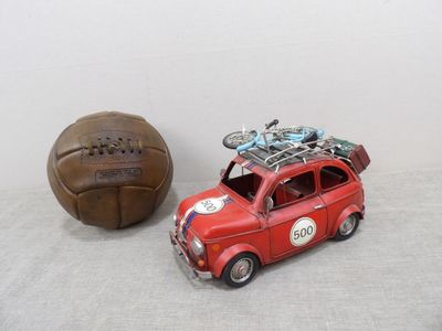 a small red car with a bike on top next to a brown ball