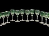 six verres à vin verts sont alignés sur une surface noire
