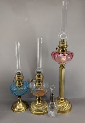 three different colored glass candlesticks on a table