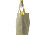 beige leather tote bag with yellow handles on a white background
