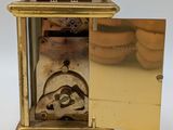 a gold clock with a door open on a white surface