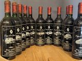 six bottles of red wine are lined up on a wooden barrel