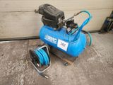 a blue air compressor sitting on the ground next to a blue hose