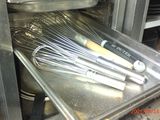 several whisks are in a metal pan in a kitchen