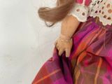 a close up of a doll wearing a dress and a hat