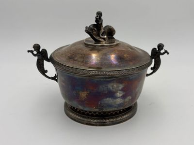 an antique silverplated bowl with a lid and two figurines on it