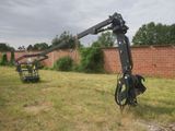 a crane that is sitting in the grass near a brick wall