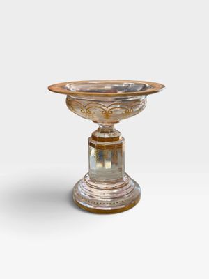 une image représentant un socle en argent et en or surmonté d'un bol en verre