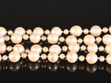 a close up of a bracelet with pearls and diamonds on a black surface