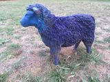 une statue bleue représentant un mouton debout dans l'herbe