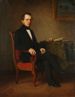portrait d'un homme en costume noir assis dans un fauteuil rouge