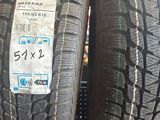 Deux pneus sont empilés sur un présentoir bleu dans un magasin