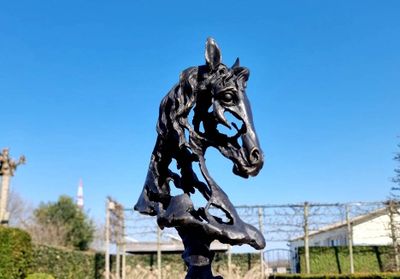 une statue de cheval sur un socle dans un jardin