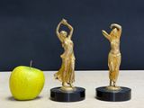 two figurines of a woman and an apple on a table