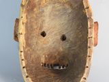a wooden mask with holes in the middle of it