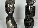 deux sculptures noires représentant un homme et une femme, posées sur une surface blanche