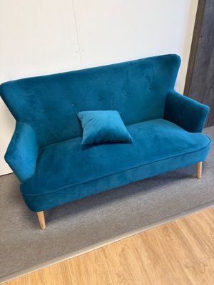un canapé en velours bleu turquoise sur lequel sont posés deux coussins