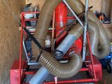 a red machine with a hose attached to it in a garage