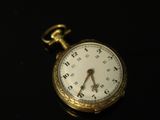 a gold pocket watch on a black surface