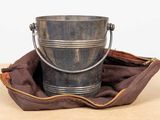 a metal bucket sitting on top of a brown bag