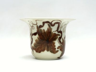 un vase blanc orné d'un motif floral marron