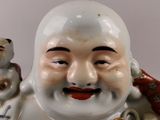 a figurine of a smiling buddha holding a gold bell