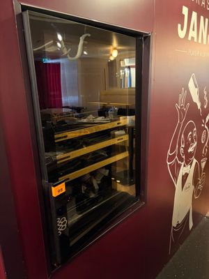 une cave à vin placée contre un mur sur lequel est accroché un tableau