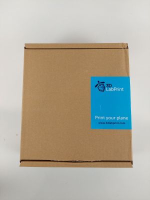 une boîte ouverte, sur laquelle est collé un autocollant bleu, posée sur une surface blanche