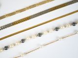 many different types of necklaces and bracelets on the table
