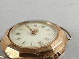 a small gold pocket watch with roman numerals on it