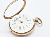a gold pocket watch with roman numerals on it