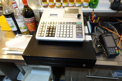 une calculatrice posée sur un comptoir, à côté de bouteilles d'alcool