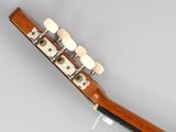 the neck of a mandolin guitar with four strings and a tuner