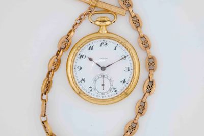 a gold pocket watch on a chain with a chain around it
